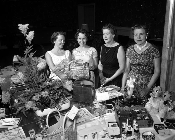 Four women pose behind a table filled with prizes and flowers which will be awarded to golfers at the Stagette Day women's golf contest. They include, from the left: Lois Mayer, Betty Vaughn, Edna Walker, and Mercedes Haen.
