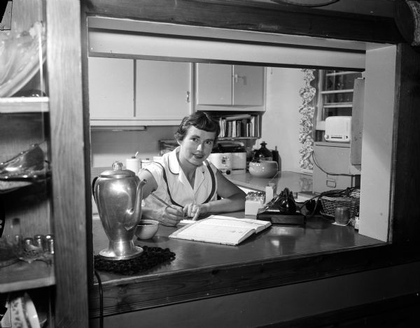 Jean Clausen sitting at a table in her kitchen while doing menu planning for her family. Part of photo spread for WSJ's Centennial Cookbook recipe contest.