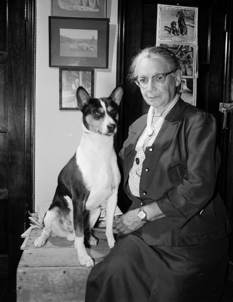 Dr. Eloise Gerry poses with "Black Mint of the Congo," a Basenji or barkless dog of Africa. Dr. Gerry, retired from the United States Forest Products Laboratory, has raised Basenjis since 1942 as one of a small number of breeders in the country. She was the only woman on the staff of the new Forest Products Lab in 1910. She did research in the field of naval stores, the production of turpentine and resins.