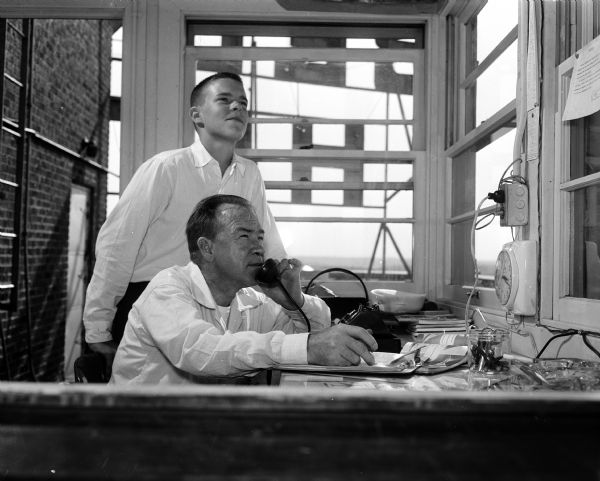 Edward Northrup (seated) and Jan Macdonald are volunteer sky watchers in the Ground Observer Corps. From the top of the Belmont Hotel, they scan the sky and report to the filter center in Chicago on all the planes in flight.