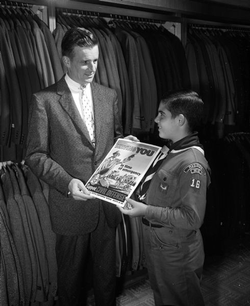 Richard Bosold, a member of the Boy Scout Troop 16 at Blessed Sacrament Catholic school, delivers one of the civil defense posters to Robert Schmitz, general manager at The Hub clothing store where the poster will be displayed.