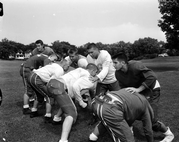 Edgewood High School linemen work out during the first football practice. Facing the camera are Dick Moore, Cyril Bohne, Mike O'Leary, and Dick DeSalvo. In a charging pose are John Malec, Frank Hebl, George Armstrong, and Ray Malec.