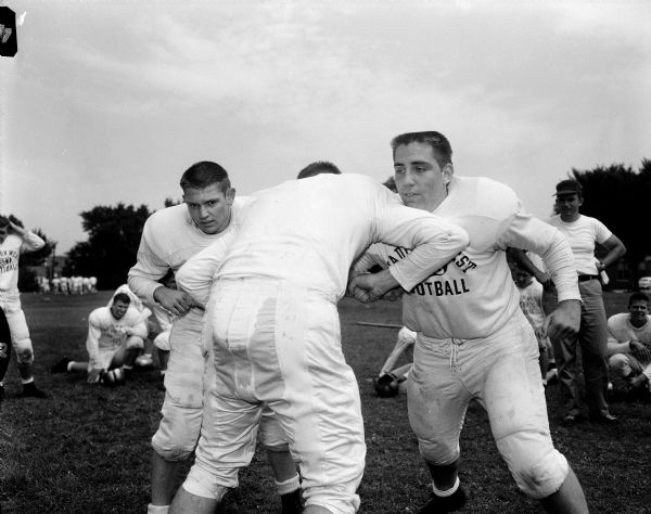 Madison West High School football players complete a drill during the first  practice. Barney Smith charges with his back toward the camera while going against Gordon Solheim and Bill Rubin.