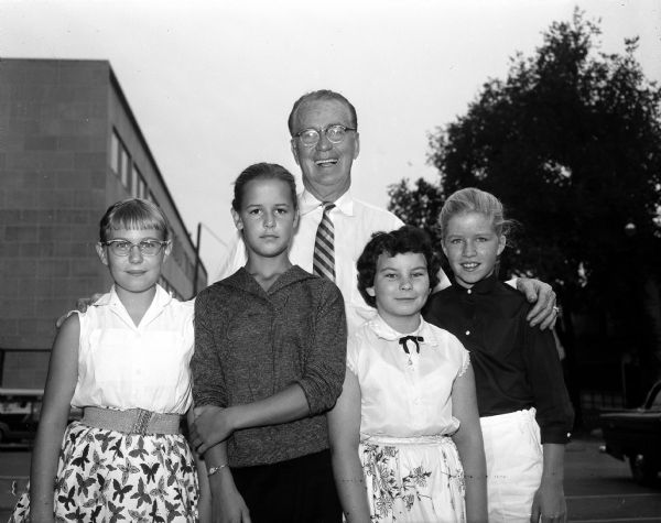 Group portrait of children from the Shorewood Hills play school who put on a carnival with the proceeds going to "Roundy's Fun Fund." With them is Joseph L. "Roundy" Couglin, sports writer for the <i>Wisconsin State Journal</i>. Left to right: Jean Hennessey, Tracy Nelson, "Roundy," Roberta Beverstein and Deedee Gale. The fun fund benefits disabled children.