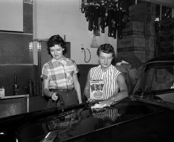Rae Carol Rocca, left, and Rita Freibutger washing and polishing a car at the Franz Haas Standard Station at 318 South Park Street during the Catholic Junior League all-girl car wash at Madison service stations. The activity will finance league projects.