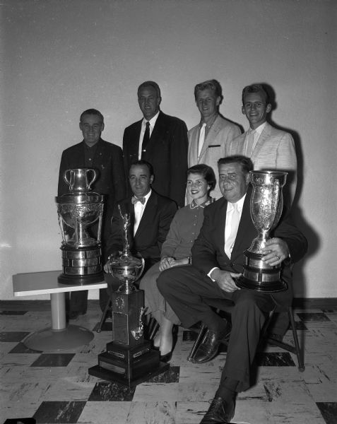 Group portrait of golfers from Madison's Nakoma Country Club who helped win state amateur trophies. Seated, left to right, are: Steve Caravello, Jill Molinaro, and Frank Molinaro. Standing, left to right: are Chet Beyler, Bill Garrott, Don Quam, and Don Christianson.
