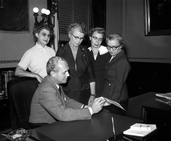 Wisconsin governor Walter J. Kohler signs a proclamation for National Business and Professional Women's Week. Looking on are, left to right: Mrs. Herbert E. (Minnie) Whipple of Madison, Mrs. B.L. Zipse of Beloit, Mrs. E.J. Smith of Mt. Horeb, and Estah Cummings of Madison. The women are all officers of the Wisconsin and Madison Business and Professional Women's Clubs.