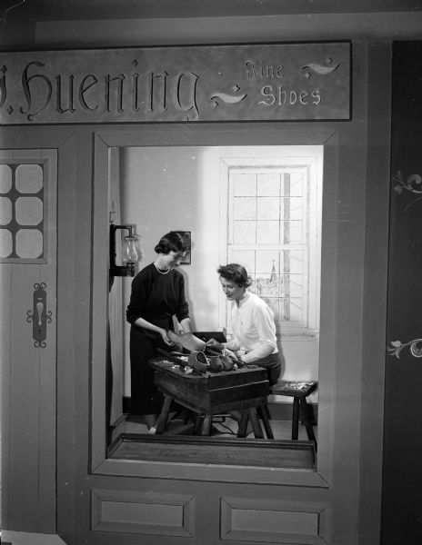 View into a German wooden shoe-making shop in The Village Green, a Wisconsin Historical Society exhibit. Shown in the shop are Marcia Harrington and Korothy Koltes, West High School students.