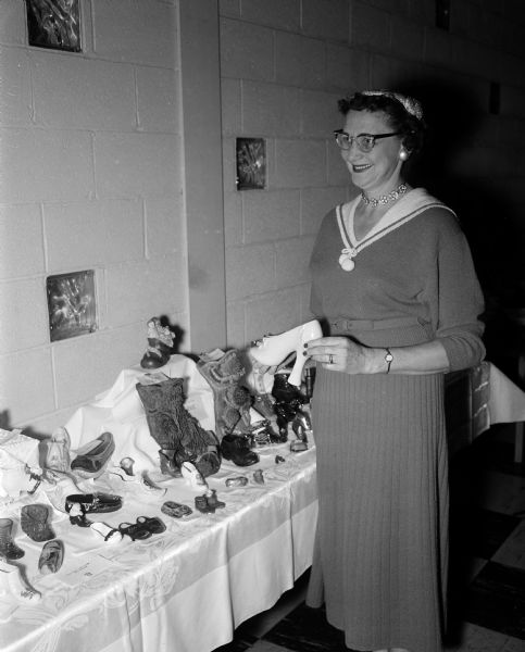 Garnet Baker stands beside part of the shoe collection she brought to the hobby show of the East Side Women's Club.