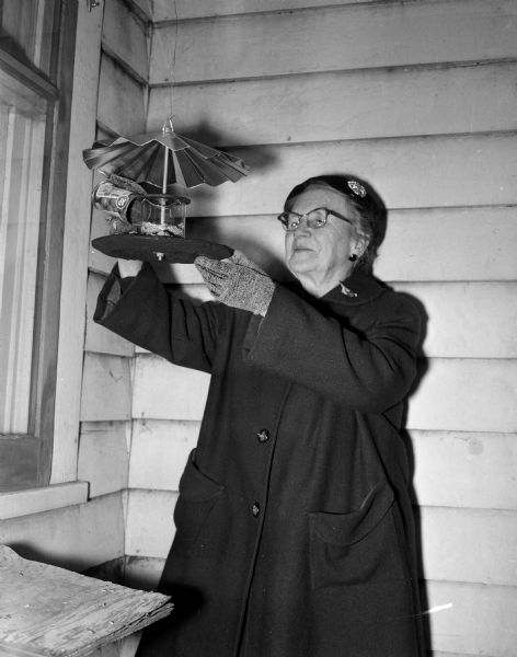 Madison Audubon Society president Mary Walker filling one of her bird feeders in preparation for the annual December 22 bird census. The metal bird feeders were designed by Mr. and Mrs. Henry Koenig of Sauk City and were sold at Madison Newspapers Inc. offices with half of the proceeds going to charity.