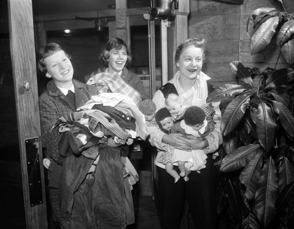 Portrait of Judy Friede of 709 Oneida Place, Kris Erickson of Old Sauk Road, and Terry Thomas of 4149 Mandan Crescent, members of Tri-Hi sorority arrive at the Unitarian Meeting House with donations of clothing and dolls to be packed and sent to Hungary.