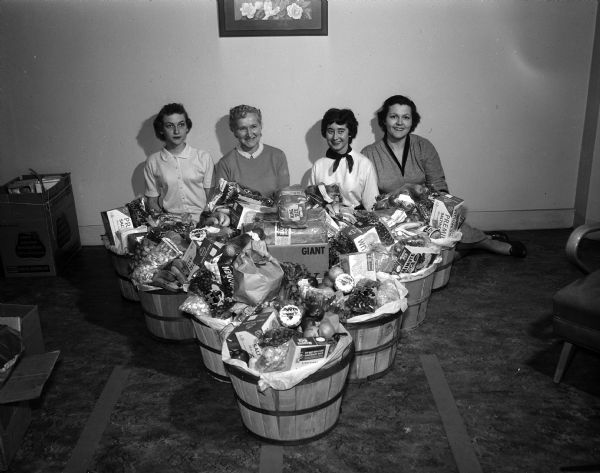 Wisconsin Telephone Company operators are shown with Christmas baskets of food to be delivered to the needy. Left to right: Barbara Gardner, Ione Wall, Vanyce Hanson, and Marie Klecker.