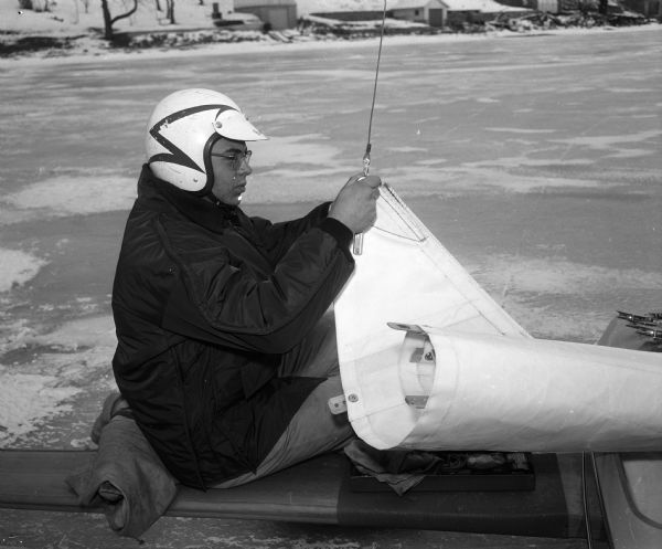 Portrait of Bill Ward as he prepares to hoist the sail on an iceboat.