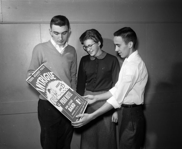 Three teenagers on the planning committee for the Teens Against Polio dance look at a poster advertising the event. Left to right: Dick Togstad, West High; Judy Cooper, West High; and Peter Mack, Edgewood High School. Peter Mack is the area Teens Against Polio chairman for southern Wisconsin.