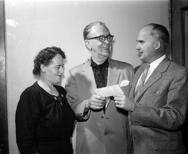 Mrs. Edith Goodman, secretary to Joseph (Roundy) Coughlin, looks on as "Roundy" presents a check to James C. Geisler, chairman of Roundy's Fun Fund, to benefit handicapped boys and girls.