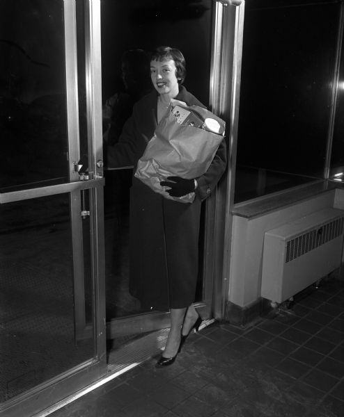 Anne Pidcoe, teacher, enters an apartment building with an armload of groceries in preparation for a dinner party.