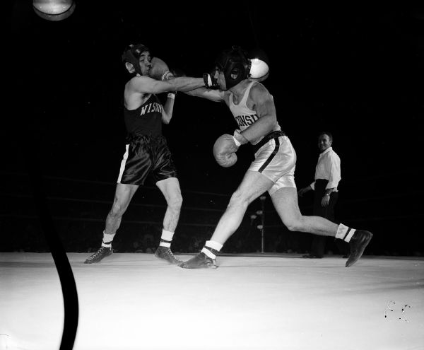 The original caption states, "Almondo Zaledon, left, and Allan Goodsitt each land a straight right on the other's jaw during the spirited third round action of their 125-pound bout in the All University finals. Goodsitt won a unanimous decision." The negative reveals that Goodsitt is stepping in to punch and that Zaledon's head is flinching back.