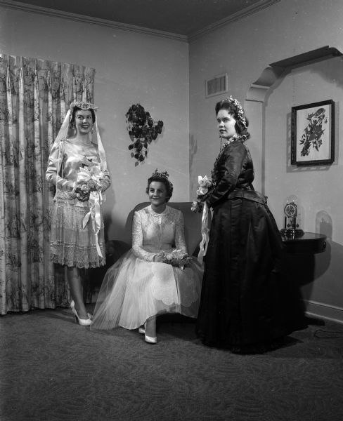 Wedding gowns representing the fashions of 73 years were presented in a bridal show sponsored by the Madison chapter of the Alumnae Association of Edgewood College. Mary Conlin, left, wears a "flapper" era short gown of ivory satin and net which was originally worn by Inez Valliant for her marriage on Dec. 28, 1927. Geraldine Nestingen, center, models her own waltz-length gown of pleated white net and lace which she wore for her marriage on June 28, 1952. Jane Bowar, right, wears the golden brown satin dress which Minnie Hess chose for her marriage on June 10, 1884.