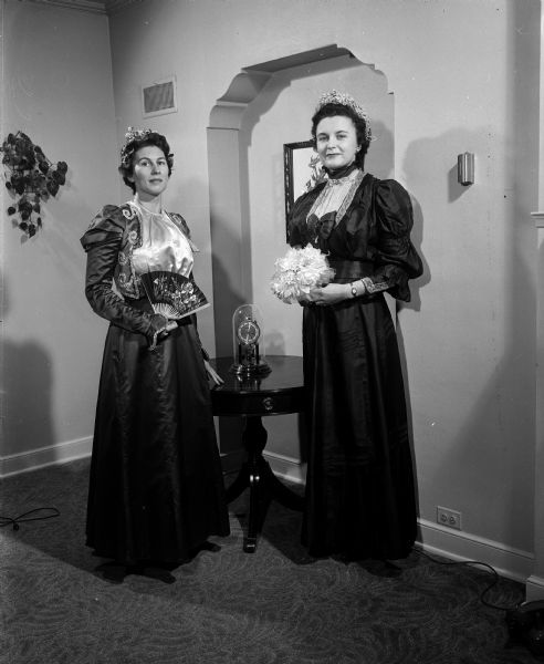 Wedding gowns representing the fashions of 73 years were presented in a bridal show sponsored by the Madison chapter of the Alumnae Association of Edgewood College. Elizabeth Maloof, left, models the royal blue and ecru gown which Ann Schulenberg wore for her marriage on May, 1, 1900. Mary Hubanks, right, models the dress of forest green changeable taffeta and beige pongee which Elizabeth Hollfelder wore for her marriage on June 6, 1905. Both gowns have leg of mutton sleeves, heavily lined skirts, and fine details characteristic of the wedding dresses of that era.    
