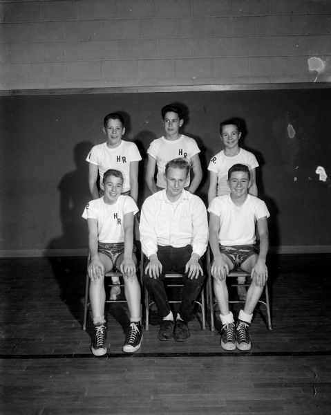 Group portrait of the Holy Redeemer Grade School basketball team, winners of division B in the Madison area Parochial League. Front row, left to right: Jay Voss, Coach Jim Morgan, and Steve Rowley. Second row: Roger Hayes, Dave Handel and Mike Hornbeck.