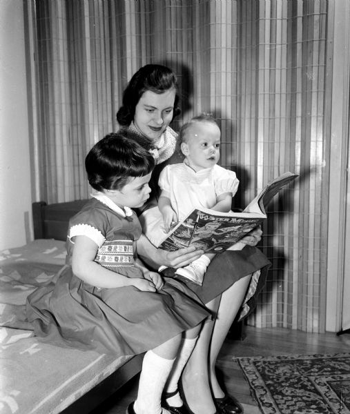 Ann Griffith reads to Jamie Lou, age 4, and Terry, 1 year, daughters of Patrick and Ardus Stone. Ann Griffith is participating in the University of Wisconsin Dames Club babysitting project.