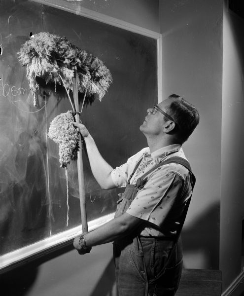 Roland Delameter cleans a blackboard in a Bascom Hall classroom during his job as a maintenance man at the University of Wisconsin. Roland and his wife, Winnie, were both seriously physically handicapped by cerebral palsy since birth. They met at Camp Wawbeek, which provides camping experience for physically handicapped adults and children. The camp is by the Wisconsin Association for the Disabled and funded by the sale of Easter Seals.