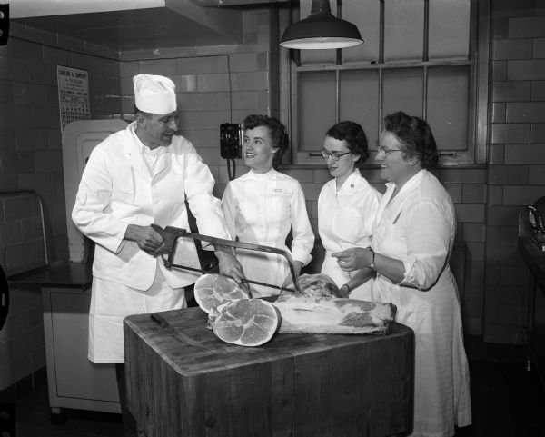 Robert Kopp demonstrates meat cutting to Shirley Walberg (intern), Janice Hinze (assistant), and Ruth Dickie (chief dietician) during the hospital dietetics presentation, a part of the University of Wisconsin Home Economics Day.