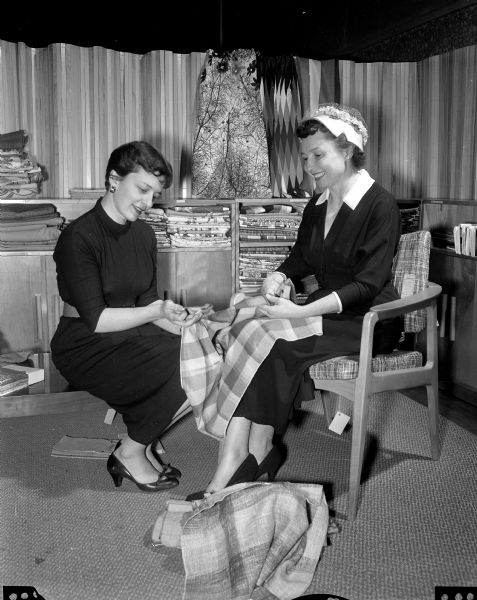 Harriett Allender Steil, interior decorator for Frautschi's and 1951 home economics graduate of the U.W., discusses drapery fabrics with Martha Schmidt, former state supervisor of home economics in secondary schools of Wisconsin.