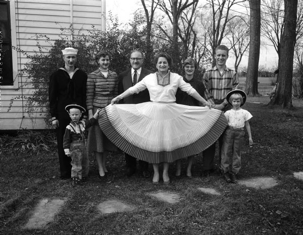 Outdoor group portrait of members of the Russell Frost family. The woman in the center is holding her ankle-length skirt wide to the sides.