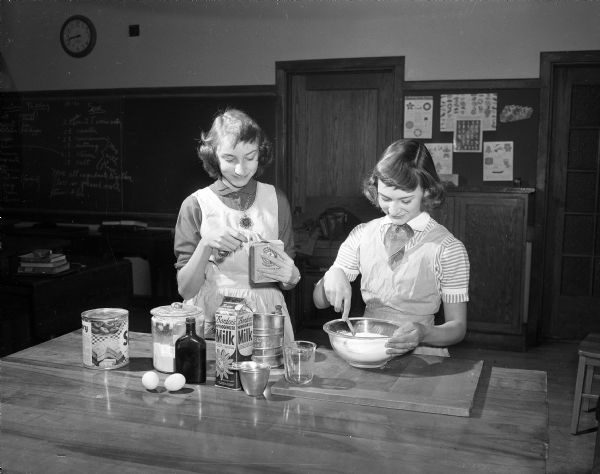Nancy Rieter and Dianne Blanchard, students in the 8th grade home economics class at West Junior High School, mixing cookie batter. The class baked several thousand Christmas cookies to be donated to the patients at the Veteran's Adminstration Hospital.