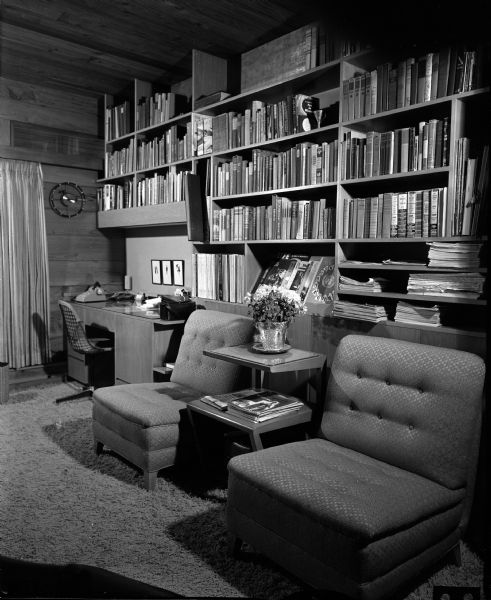 View of the den in the Gerald and Joyce Bartell home at 3938 Plymouth Circle. The living room fireplace is visible on the other side of the wall of bookshelves.