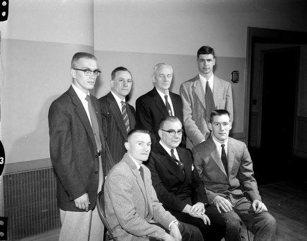 Group portrait of guests at an annual banquet for Wisconsin gymnasts sponsored by the Madison Turners. Front row, left to right: Bob Bowen, co-captain of the Wisconsin gymnastic team for the 1957-58 season;  Peter Wittock, president of the Turners and Dale Karls, co-captain of the team. Back row: Ron Kostroski, member of the student athletic board; Dean Mory Wisconsin coach; and Rober Nieman and Tom Kinsey, chairmen for the Turners.