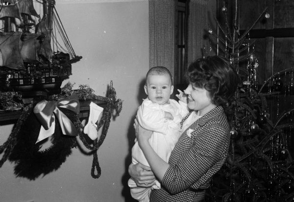 Patricia Fitzpatrick is held by her mother (?), Frances Risdon Fitzpatrick. The house is decorated for Christmas. Patricia was born Aug. 26, 1943 and her father was managing editor of the <i>Wisconsin State Journal</i>.