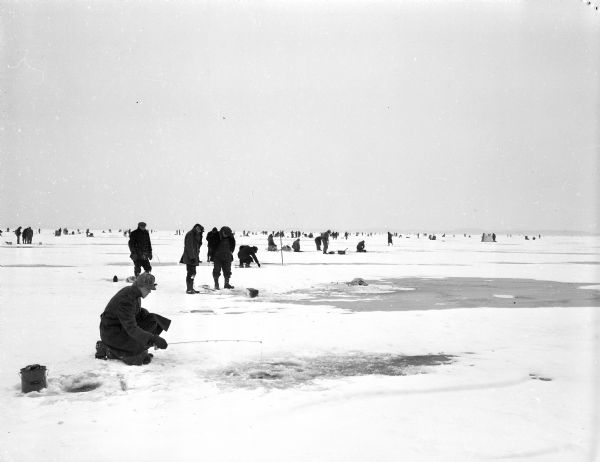 Hundreds of persons from all parts of southern Wisconsin descend on Lake Mendota to fish through the ice for perch and other pan fish. The picture was taken from a spot about a mile out from Maple Bluff.