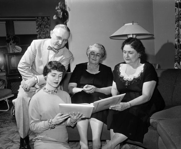 Molly Moore, lower left, showing her bridal book and silver service to her parents and the mother of her fiance. Seated in back of Molly is, left to right: Forrest F. Moore, Mrs. Wallace Conlin, and Delores Moore.