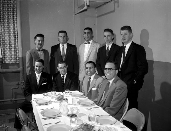 Group portrait of nine men and teen athletes. Sitting left to right are Bob Kessenich; Jack Nagle, Marquette University basketball coach; Coach Dick Trotta;and Bob Patrich, toastmaster. Standing left to right, are Dave Williamson, Joe Meffert, John Ripp, Bill Diederich, and Dr. Knight Bakke.