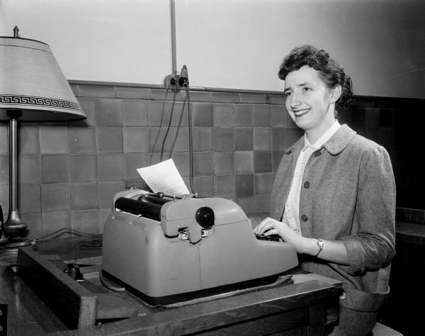 Portrait of Jacqueline Miller, seated at a desk typing a job resume.