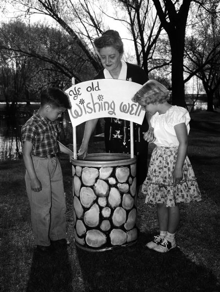 Lillian Simonson, Altrusa Club member and Marquette School principal, is shown giving a preview of a wishing well to youths Jerry Bailey and Janet Dahl.
