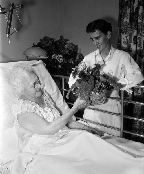 Madison General Hospital Junior Aide volunteer Betsy Dye delivers a plant to Mrs. M.C. Palmer at her bedside.