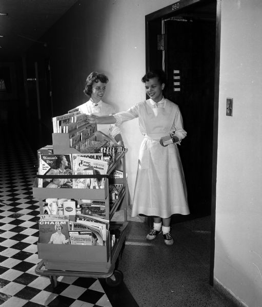 Madison General Hospital Junior Aides Helen Bernstein and Bonnie Rejahl use a cart full of magazines, candy and other items for sale to bring to patient's rooms at the hospital.