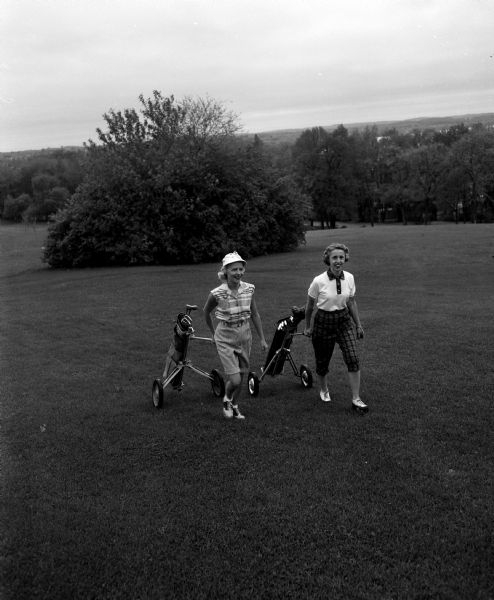 Hariett Narowetz and Irene L. Marsh pull their golf bags across the golf course.