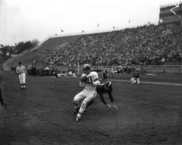 Alumni football player Elroy (Crazylegs) Hirsch catches a pass during the University of Wisconsin's Varsity vs. Alumni football game. Bill Hobbs is on the ground.