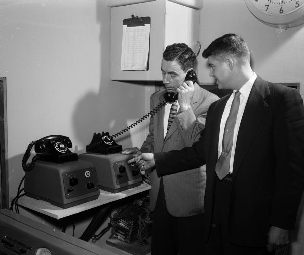 The WIBA automatic telephone system which will give latest baseball scores is tested on first day of operation. Shown testing the phones are Norman Hahn, WIBA chief engineer and Mitchell Smith, telephone engineer.