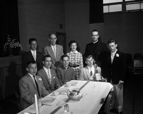 A group gathers during the annual Immaculate Heart of Mary school athletic banquet. Left to right: (seated) Tom McCulloch, Doug Wenger, Gerald Sweeney, and Bob Scott. (Standing) Mike Brown, Cecil Kielley, Marianne (Johnnie) Zeier, Rev. Lawrence Kieffer, and John Robertson.
