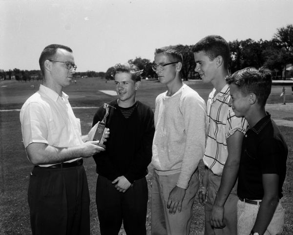 Group portrait of the winners of the JCC junior golf tournament. Left to right: Dick Wilson, tournament chairman presents the trophy to first place winner Dennis Pearson; Gilbert Thompson, Bill Haberman, and Tim Zwettler.
