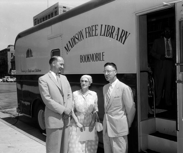 Mayor Ivan Nestingen; Head Librarian Helen Farr; and Library Board Member A. Kermit Frater stand outside Madison Public Library's new bookmobile. An unidentified man is standing in the doorway inside the bookmobile.