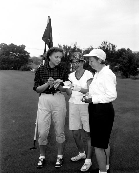 Three women golfers compare scores at the second round of the monthly inter-club play at Blackhawk Country Club. From left are Jane Savidusky of Maple Bluff, Jeanette Thomas of Nakoma, and Helene McAndrews of Blackhawk.