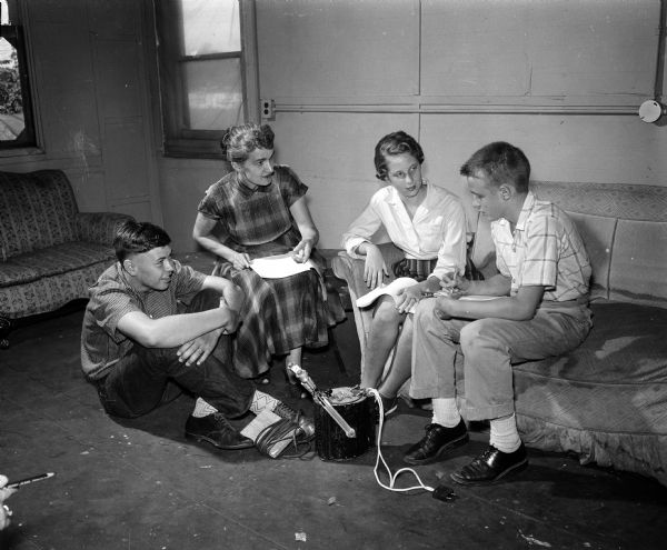 A chamber drama, "Johnny Pye and the Fool Killer," was one of the features planned for the tenth anniversary program of the Madison Youth Summer Theater. Mrs. Edmund Zawacki, current director of the Madison Youth Summer Theater, is discussing cues with the theater electrician, Steve Bracker, extreme right. Taking part in the discussion are two of the young actors, Larry Oppriecht, left, and Georgi Bohrod, seated on the couch.