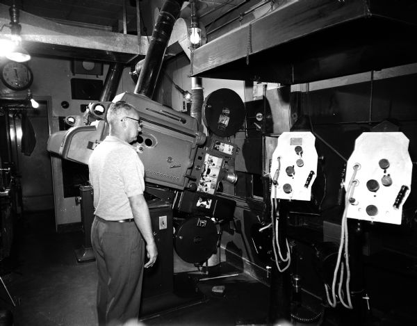 Harry Schuler mans the two projectors in the Orpheum Theatre projection booth. At the right are two of the spotlights used for stage shows.