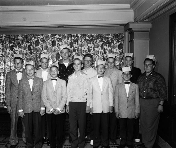 Group portrait of twelve <i>Wisconsin State Journal</i> carrier boys from southwestern Wisconsin who were honored with Inland Daily Press awards for their outstanding work. They are wearing traditional pressmen's caps which printing crews make from folded newspapers.